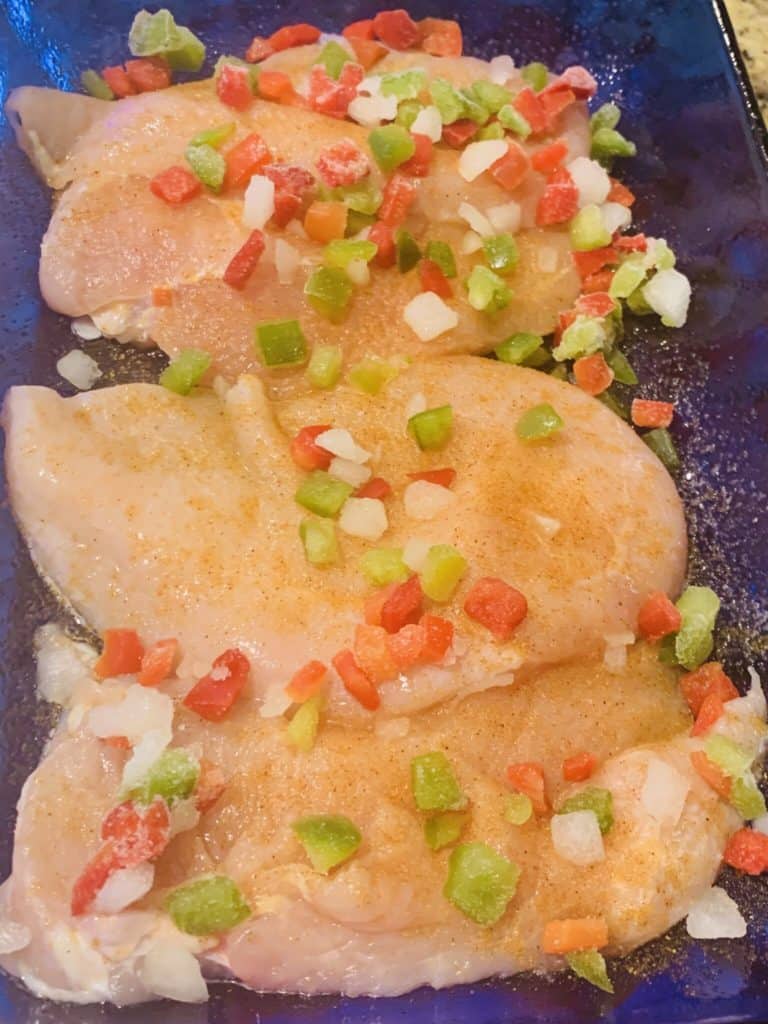 raw, seasoned chicken breasts with bell pepper and onion blend