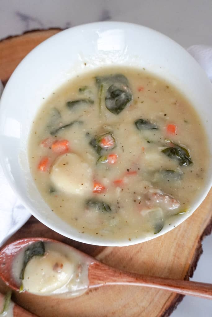 close up view of zuppa toscana with a spoon beside it