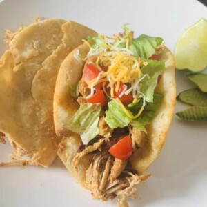 plated chalupas beside avocado slices, lime wedge, and pepper