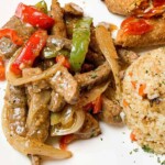 pepper steak on a plate with rice and egg roll