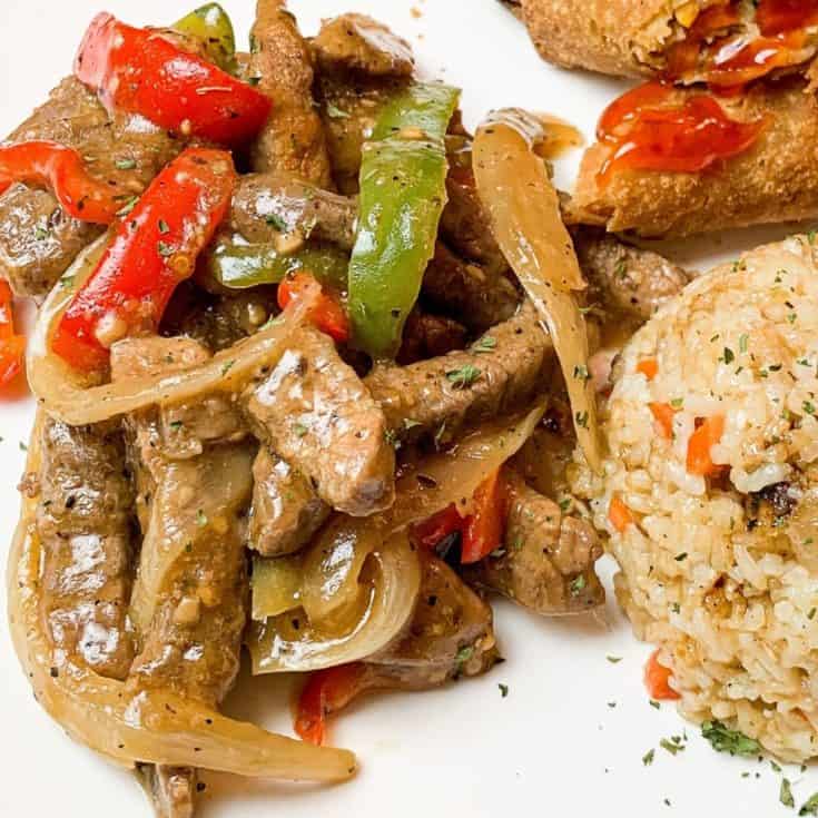 pepper steak on a plate with rice and egg roll