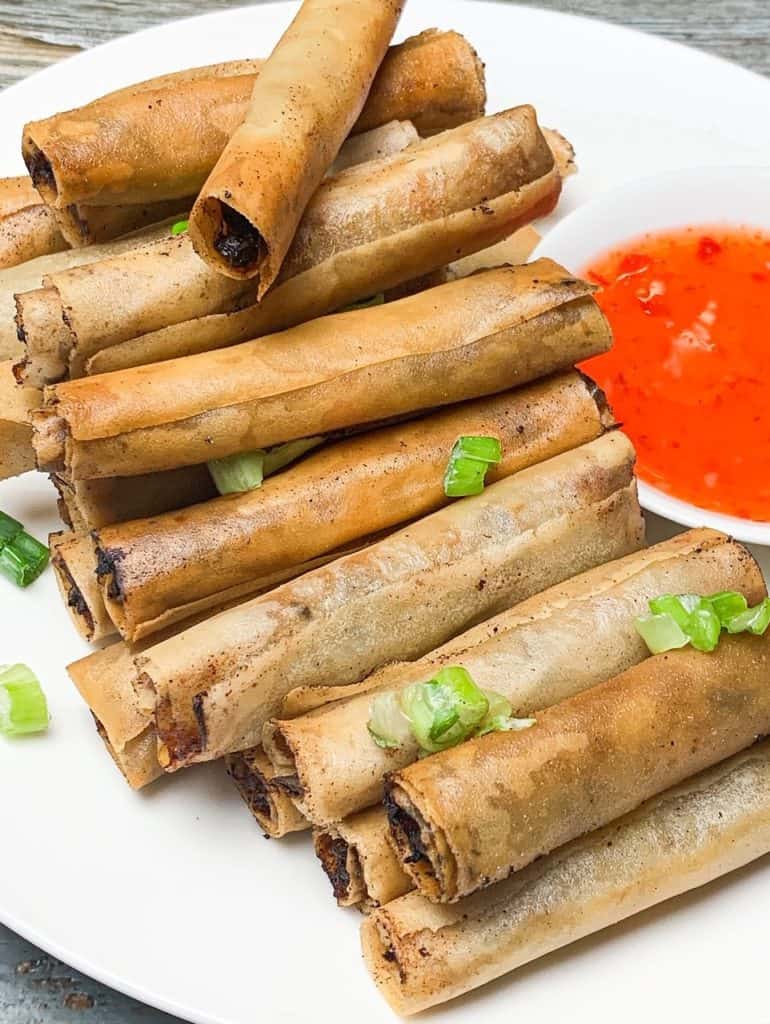A tray of homemade lumpia with a side of sweet chili sauce