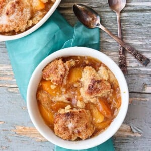 Peach Cobbler in bowl on the table with a spoon next to it