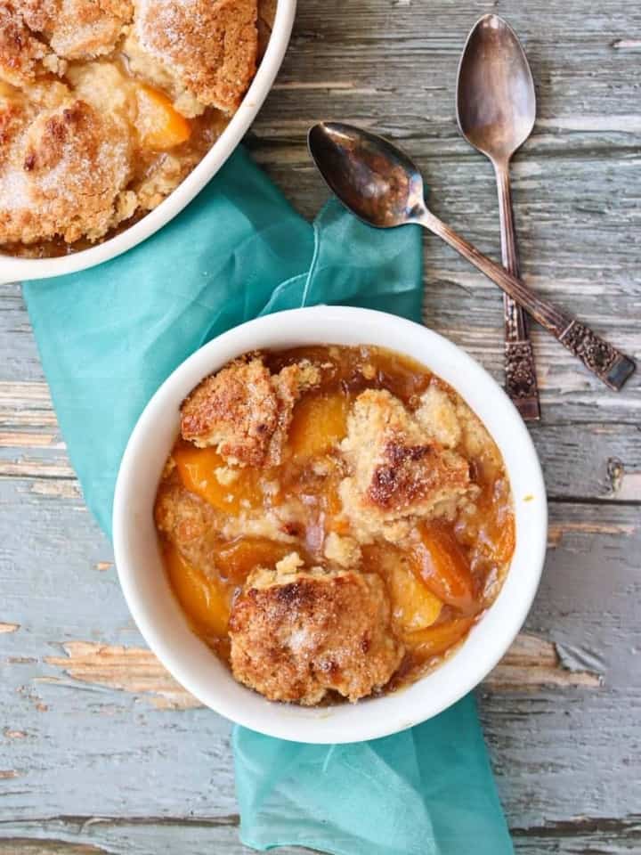 Peach Cobbler in bowl on the table with a spoon next to it