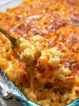 close up view of pan of southern macaroni and cheese with a spoon inserted, removing a scoop