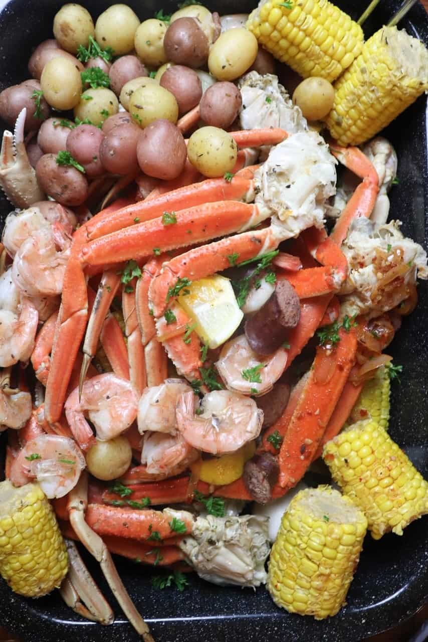 seafood boil in a baking dish with crab legs, corn, and potatoes