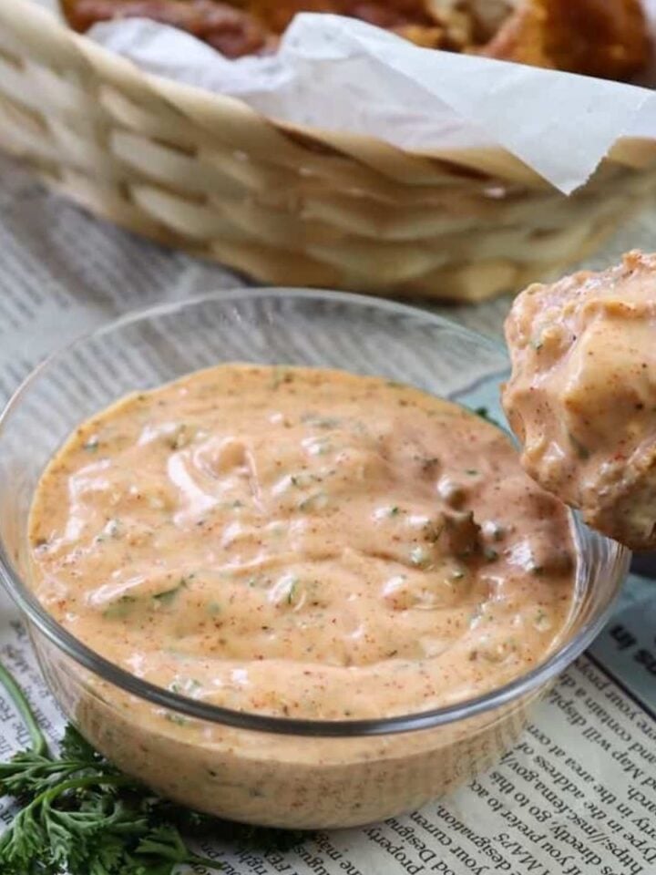 bowl of cajun tartar sauce with a piece of fish dipped in it