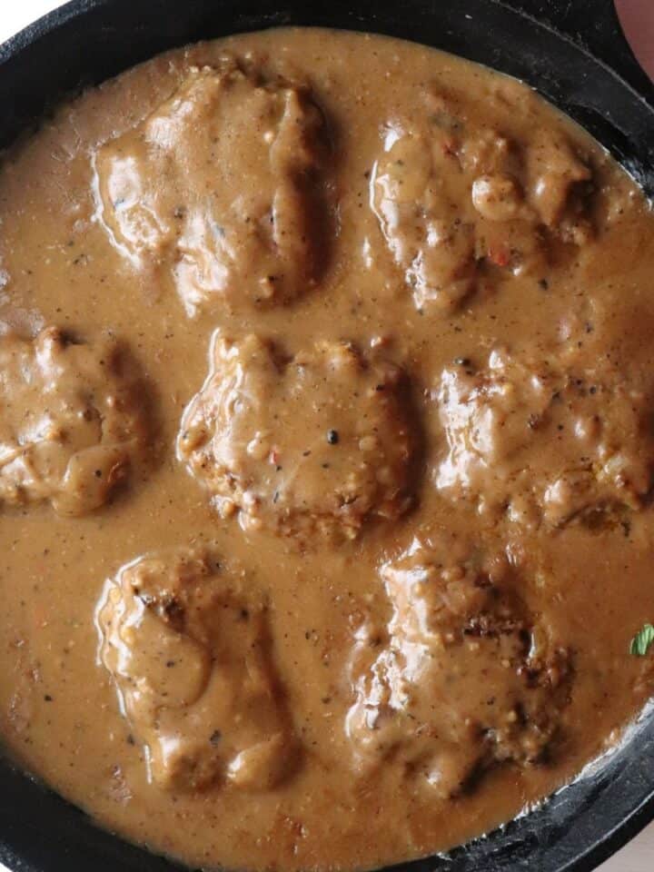 hamburger steaks in a skillet smothered with brown gravy