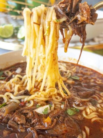 a noodle pull of birria ramen with beef in a bowl