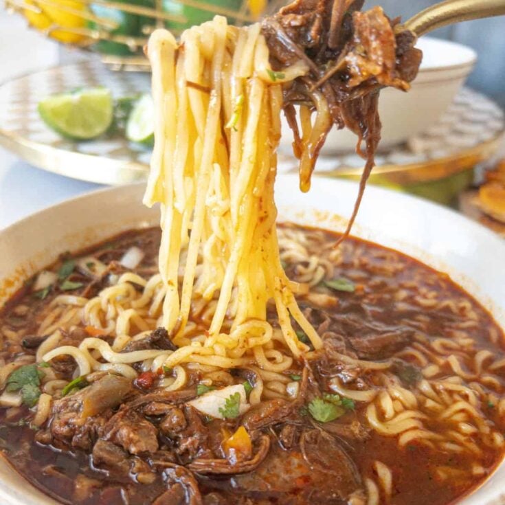 a noodle pull of birria ramen with beef in a bowl