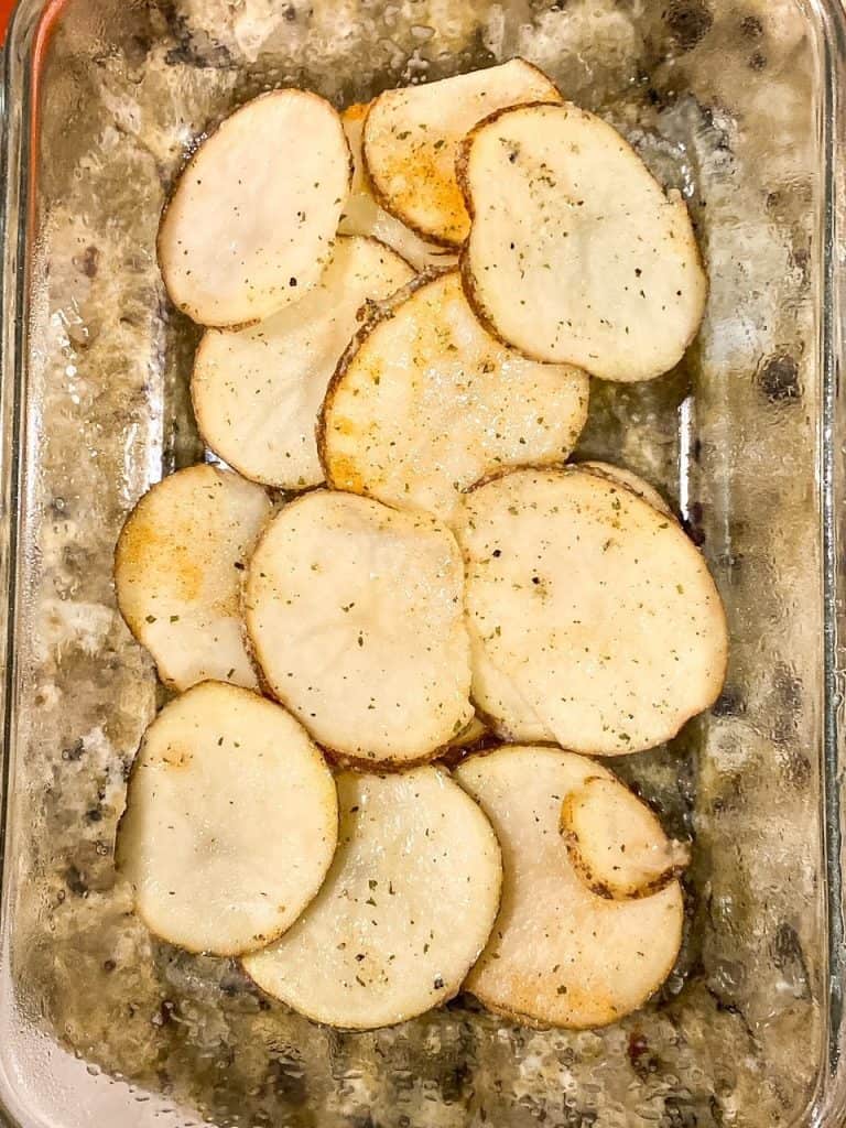 layering Cheesy Bacon Ranch Scalloped Potatoes in a dish