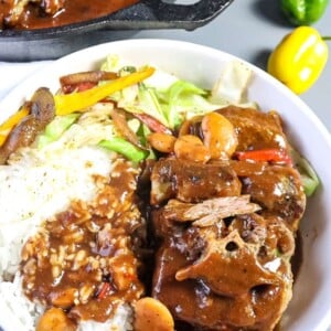 oxtails plated in a bowl with rice and cabbage