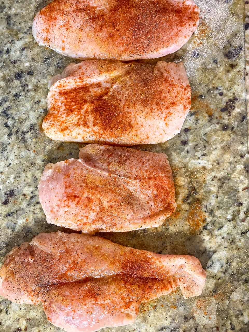 chicken breast on cutting board with seasoning