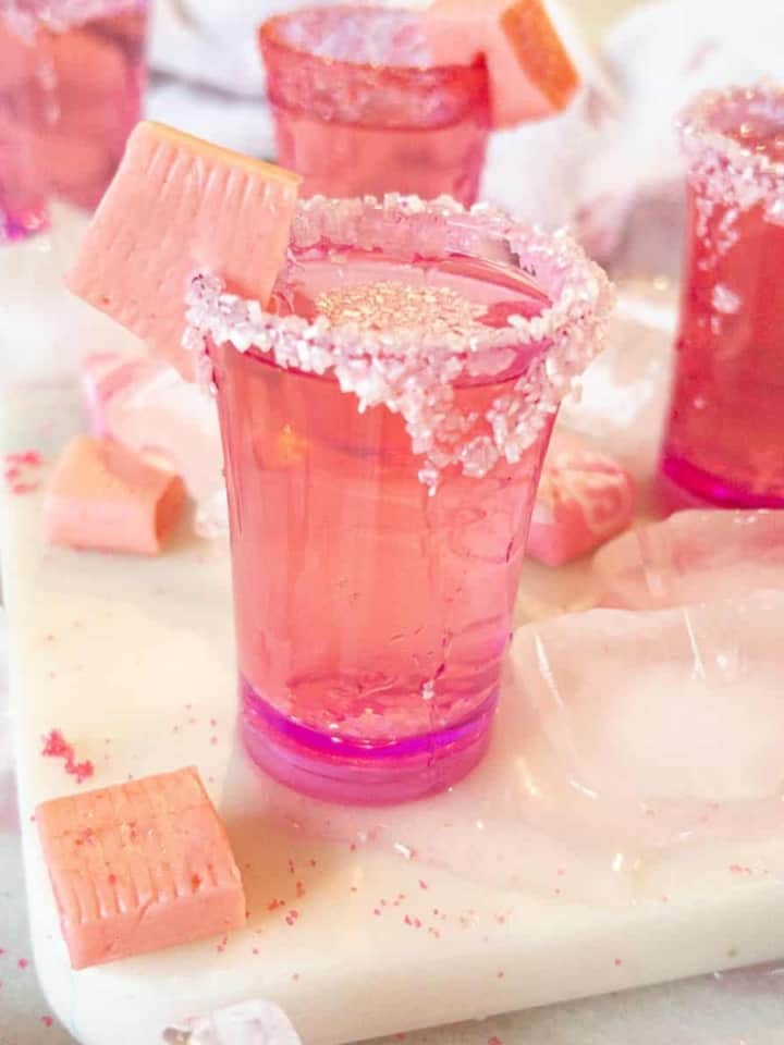 pink starburst shots on a table with ice around them