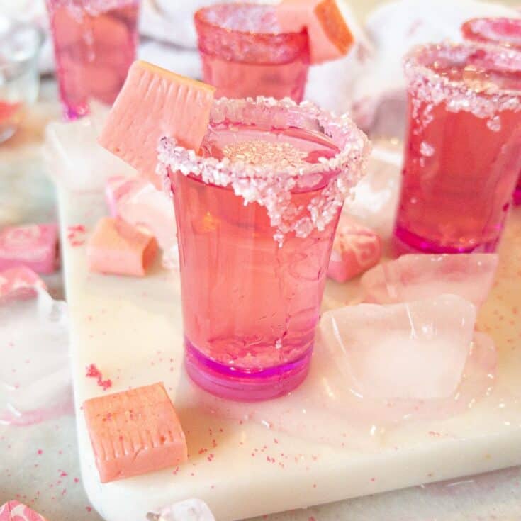 pink starburst shots on a table with ice around them