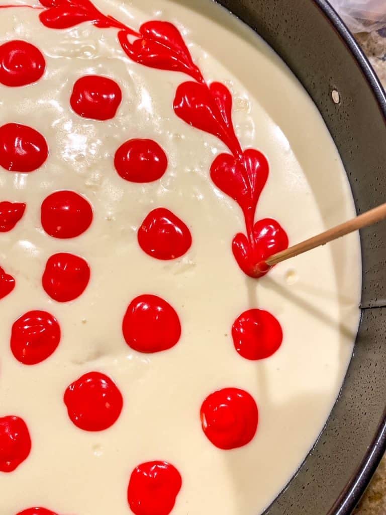 swirling red food coloring into cheesecake