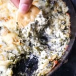 dipping a cracker into spinach dip