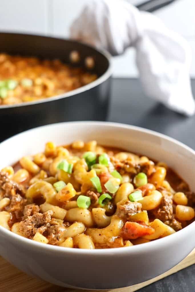 A bowl of Chili Mac and Cheese with a pot of more in the background.