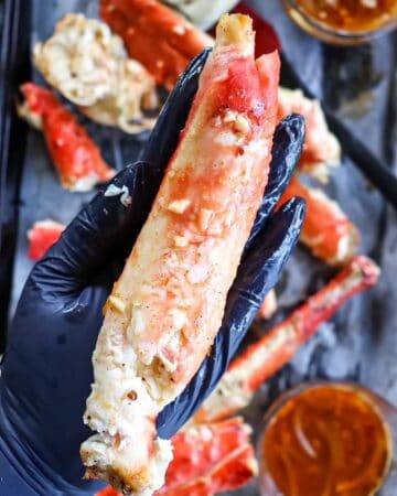 a piece of deshelled king crab held in the palm of a hand to show how large it is