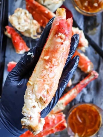 a piece of deshelled king crab held in the palm of a hand to show how large it is