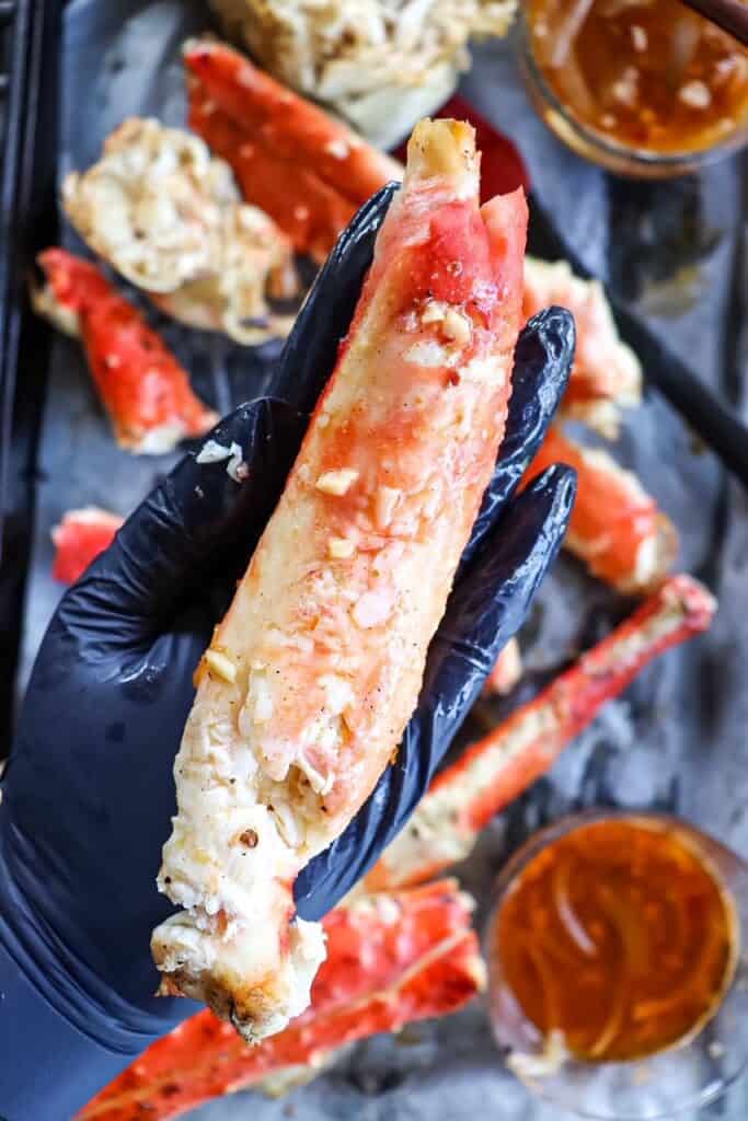 a piece of deshelled king crab held in the palm of a hand to show how large it is