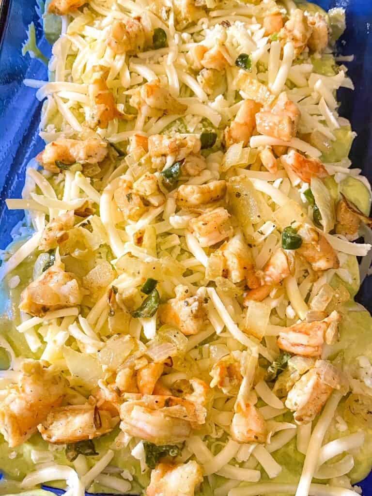 shrimp enchiladas prepared in a dish before they are baked