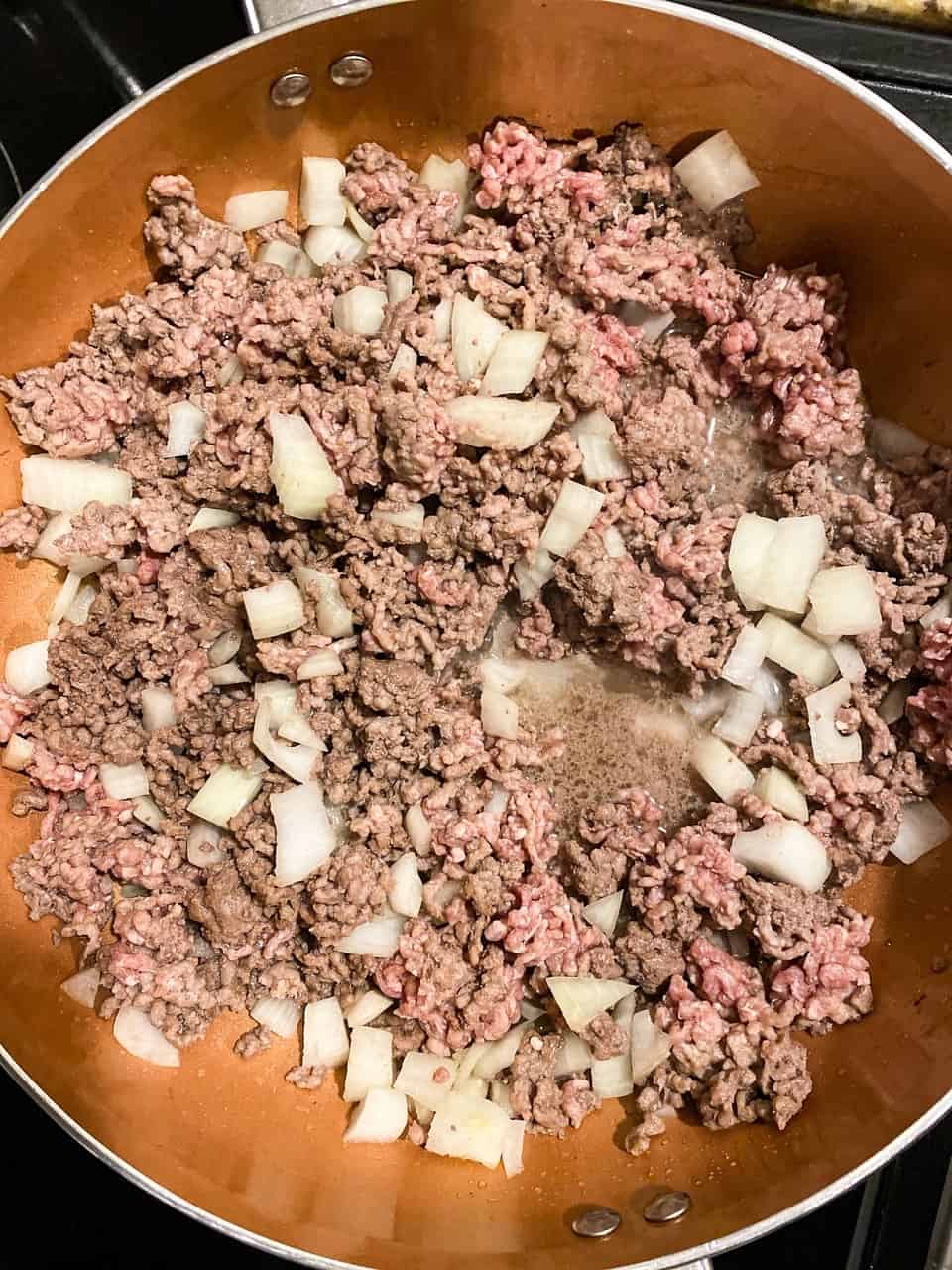 skillet with ground beef and onions cooking