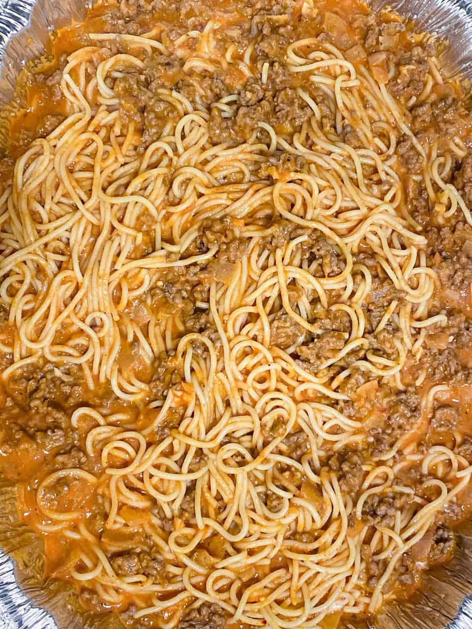 tray with spaghetti mixed with sauce ready for the oven