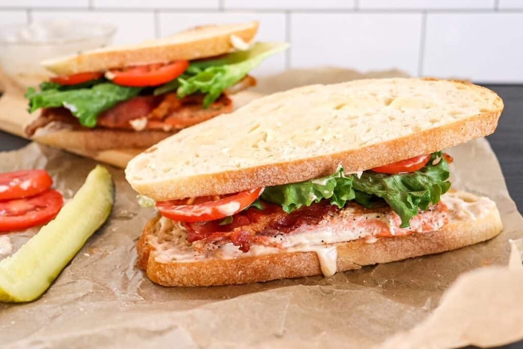 blackened salmon BLT sandwich on a cutting board