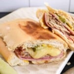 cuban sandwiches cut in half on a plate with the cheese oozing out