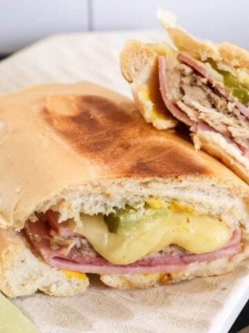 cuban sandwiches cut in half on a plate with the cheese oozing out