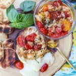 grilled brie on a cutting board with a tomato herb compote for serving