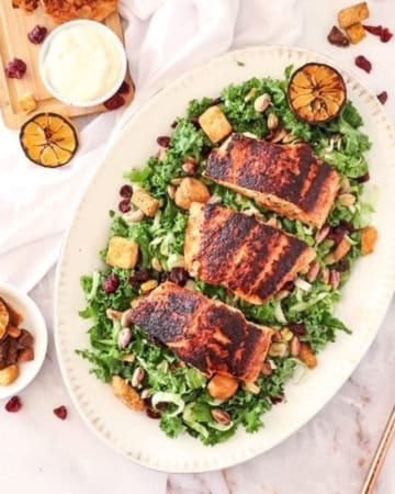 overhead of kale salad with blackened salmon on a platter