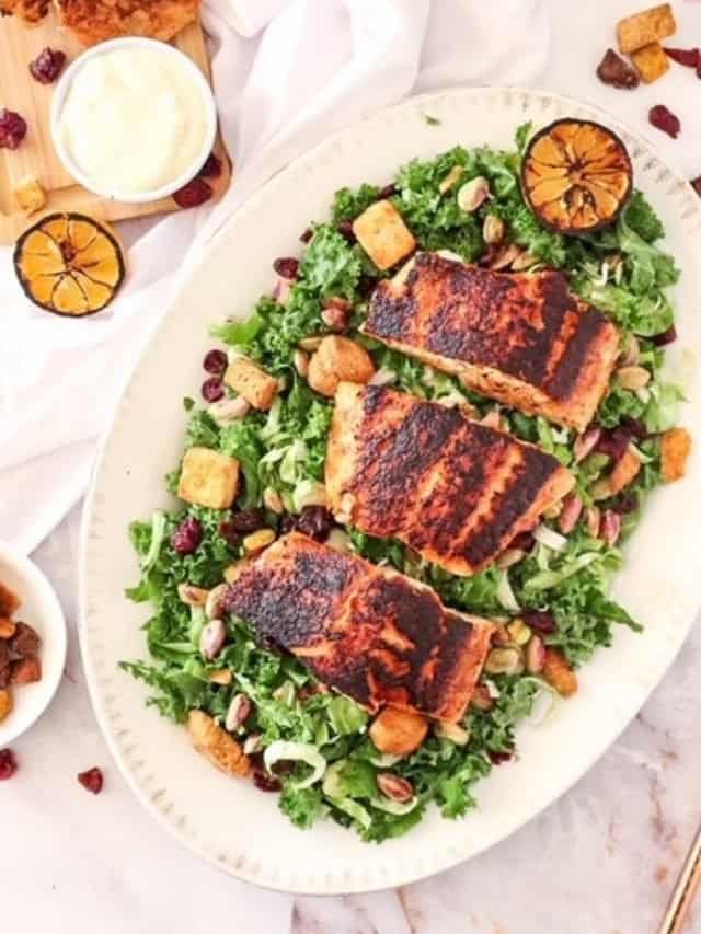 overhead of kale salad with blackened salmon on a platter