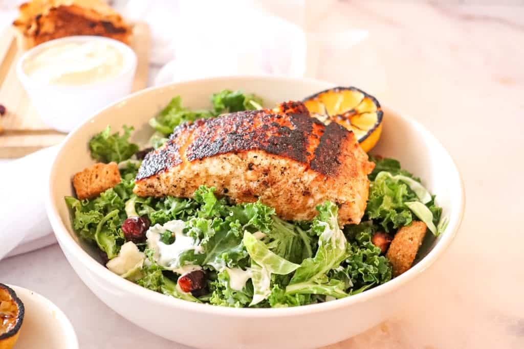 photo of kale salad in a bowl with blackened salmon