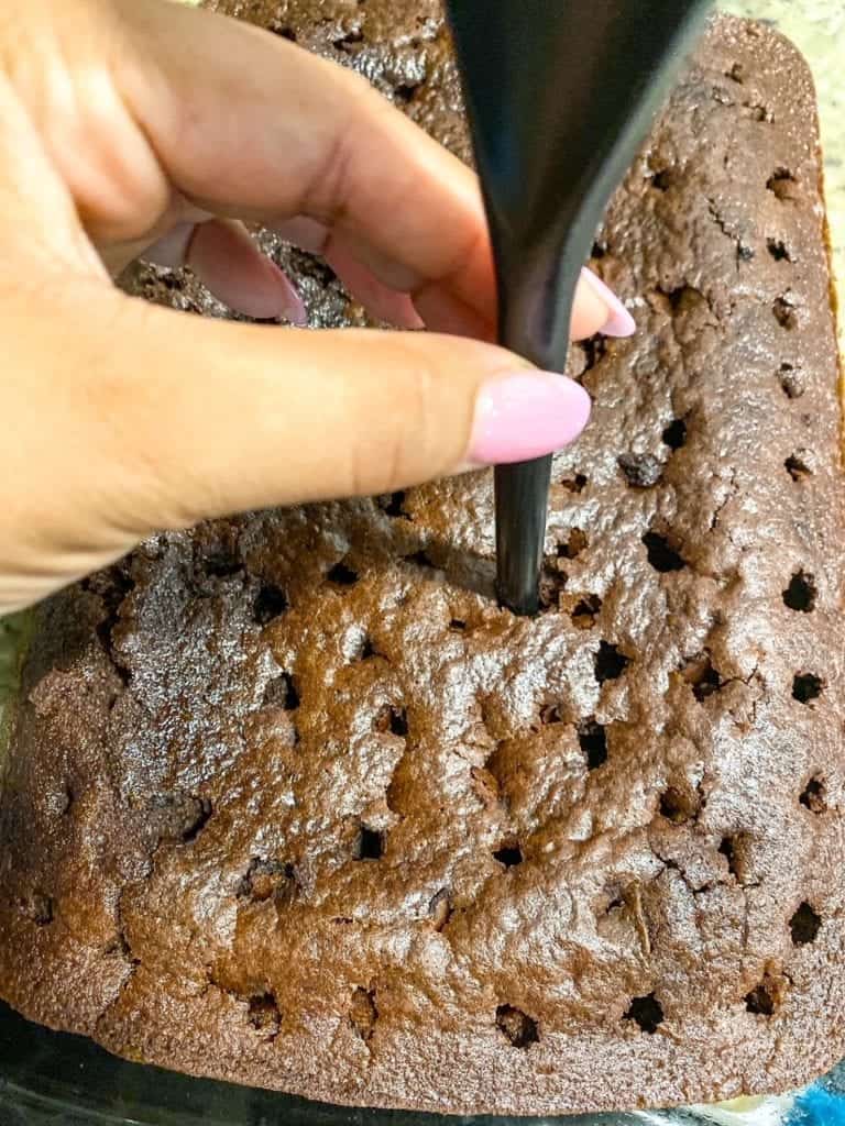 poking holes in the cake with the back of a spoon