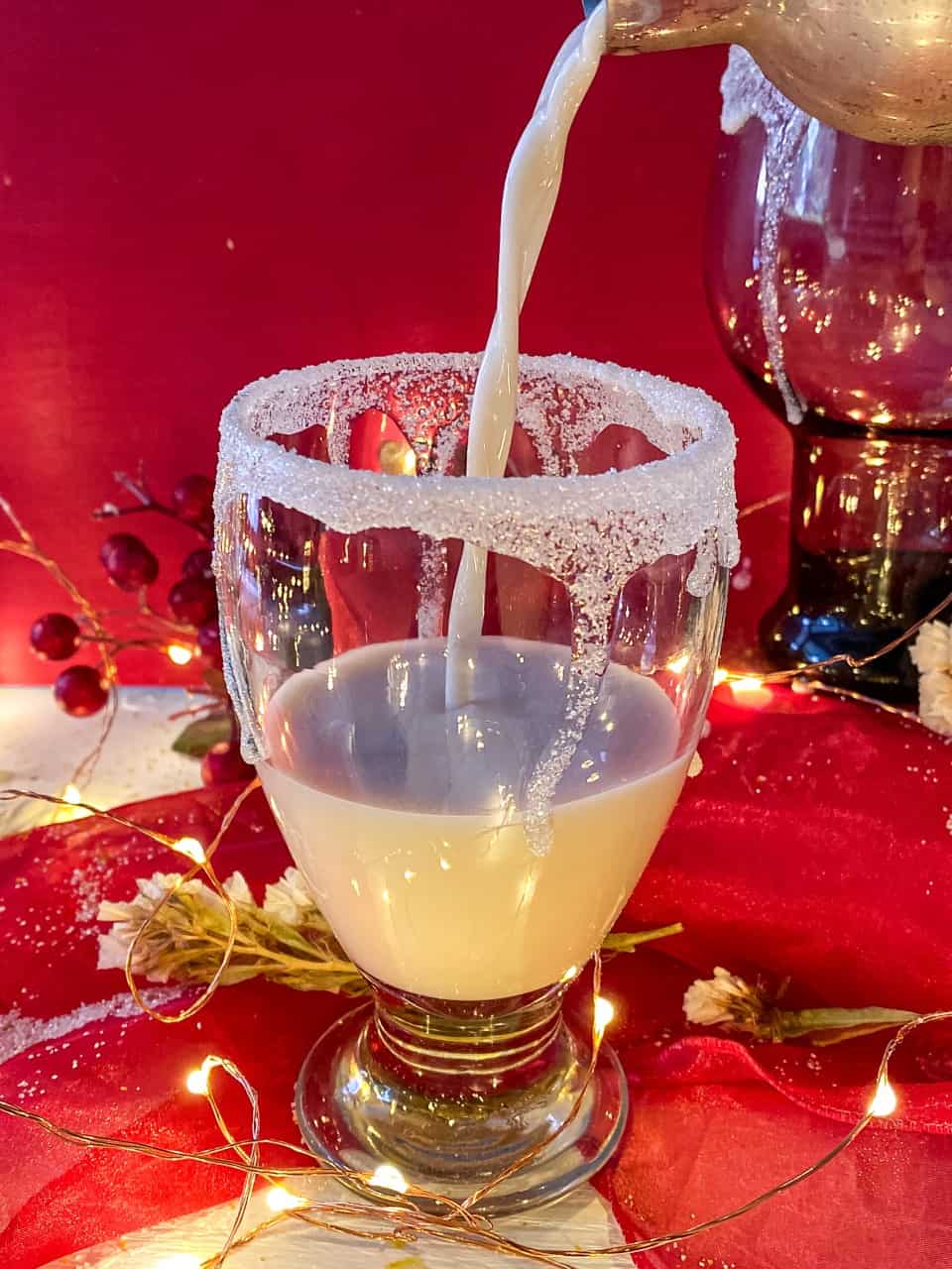 pouring white chocolate martini into a glass with a garnished rim