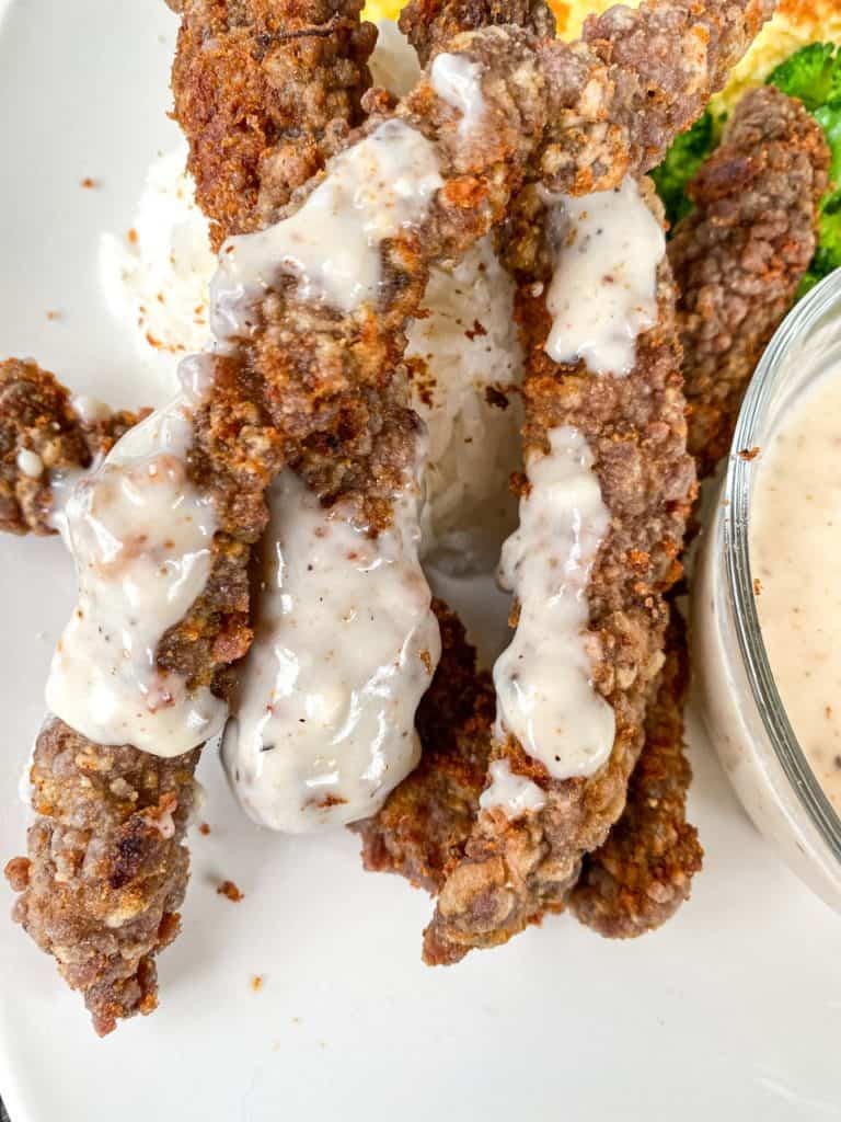 fried steak fingers with country gravy drizzled on them