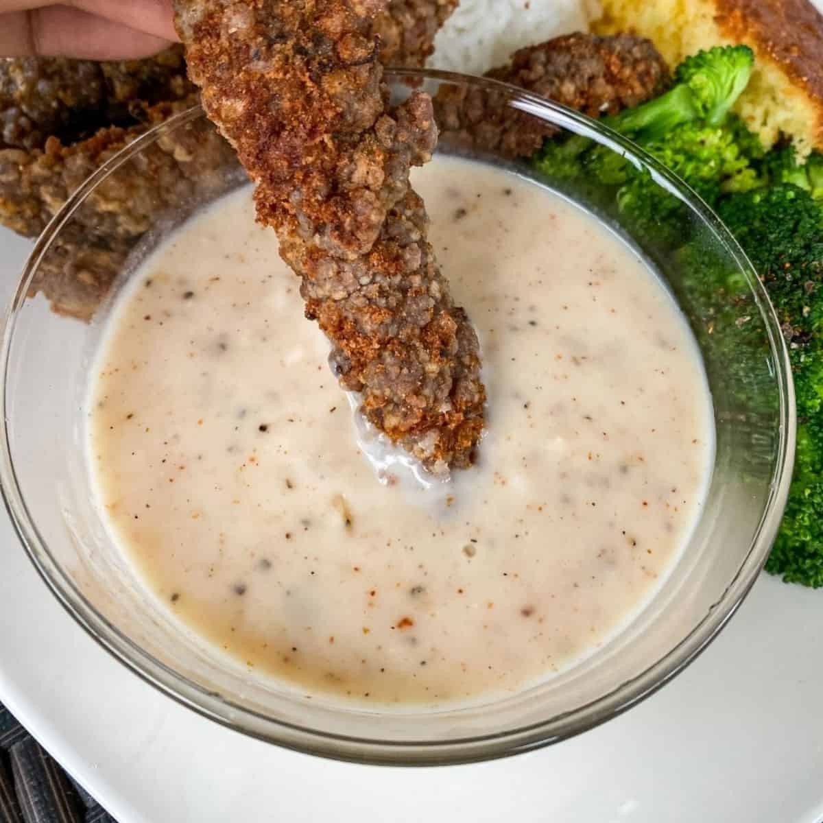 fried steak dipping into homestyle gravy
