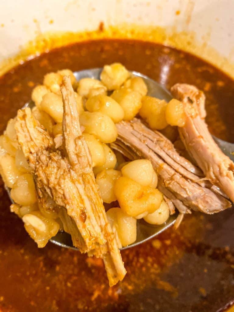 Adding hominy to the pork broth.