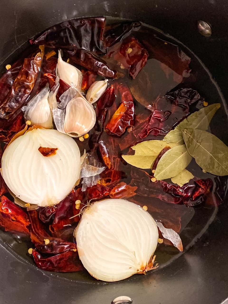 dried chiles and onions in a pot of water to make pozole rojo