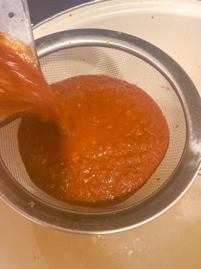 Straining the red chile sauce