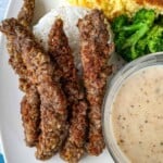 Plated chicken fried steak fingers with gravy, broccoli, cornbread, and gravy