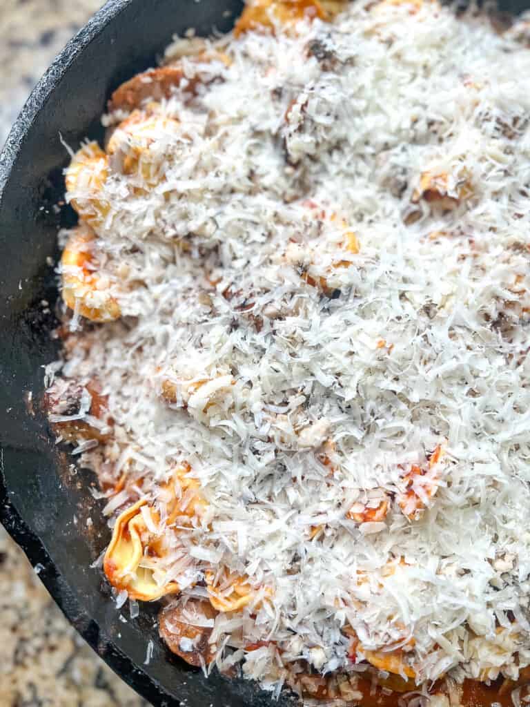 Italian sausage pasta bake with shredded cheese on top that has not been melted