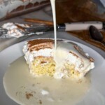 eggnog tres leches with eggnog pouring on a piece of cake