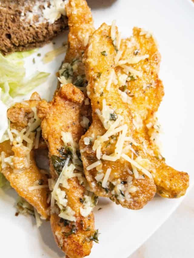 garlic parmesan chicken tenders on a plate with salad and bread