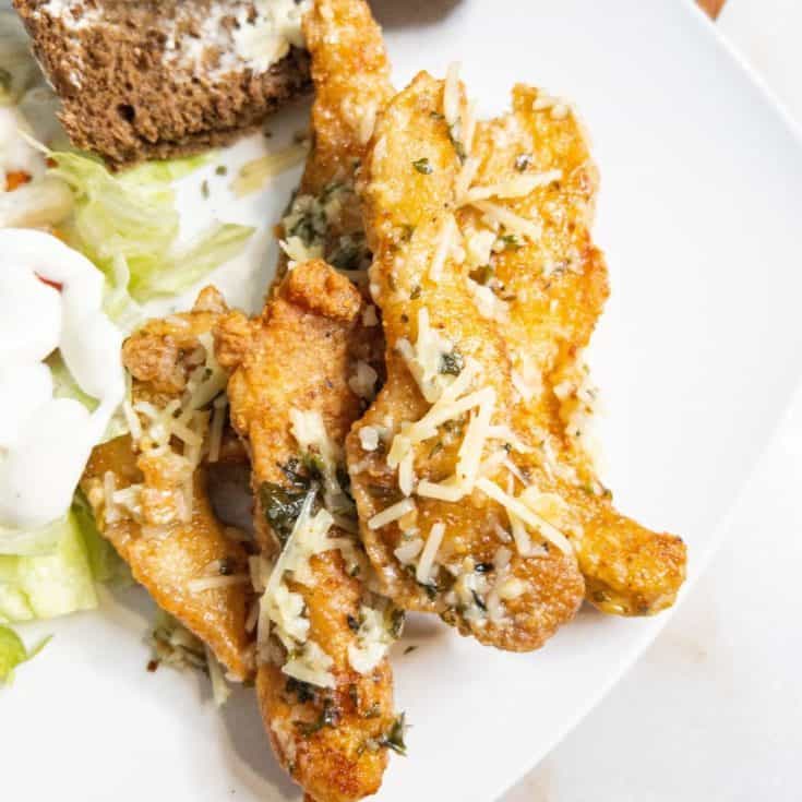 garlic parmesan chicken tenders on a plate with salad and bread