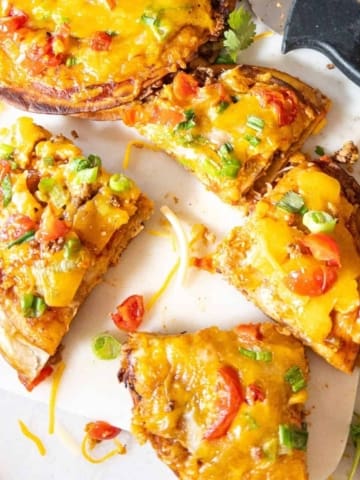 Mexican pizza on a cutting board cut into quarter