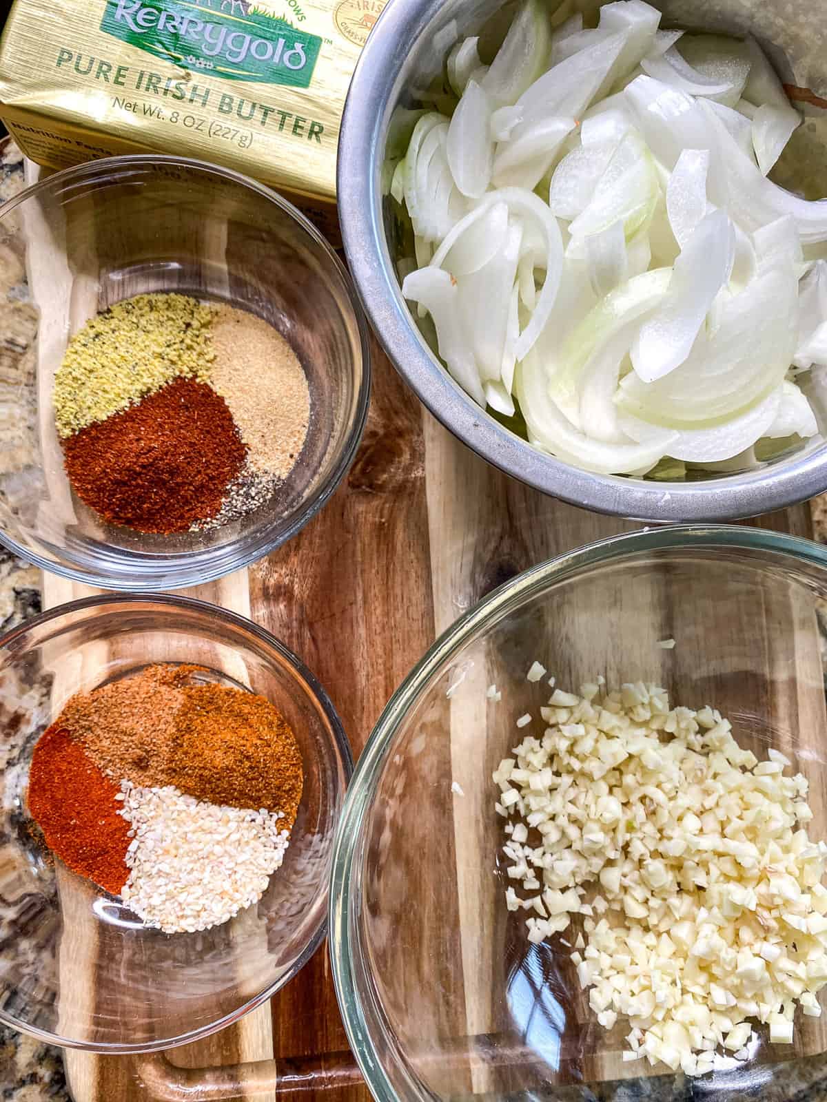 an overhead view of chopped onions and garlic as well as seasonings in a bowl