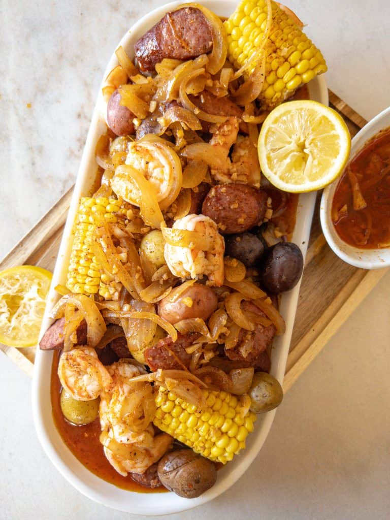 shrimp corn sausage and potatoes on a platter with garlic butter sauce on it